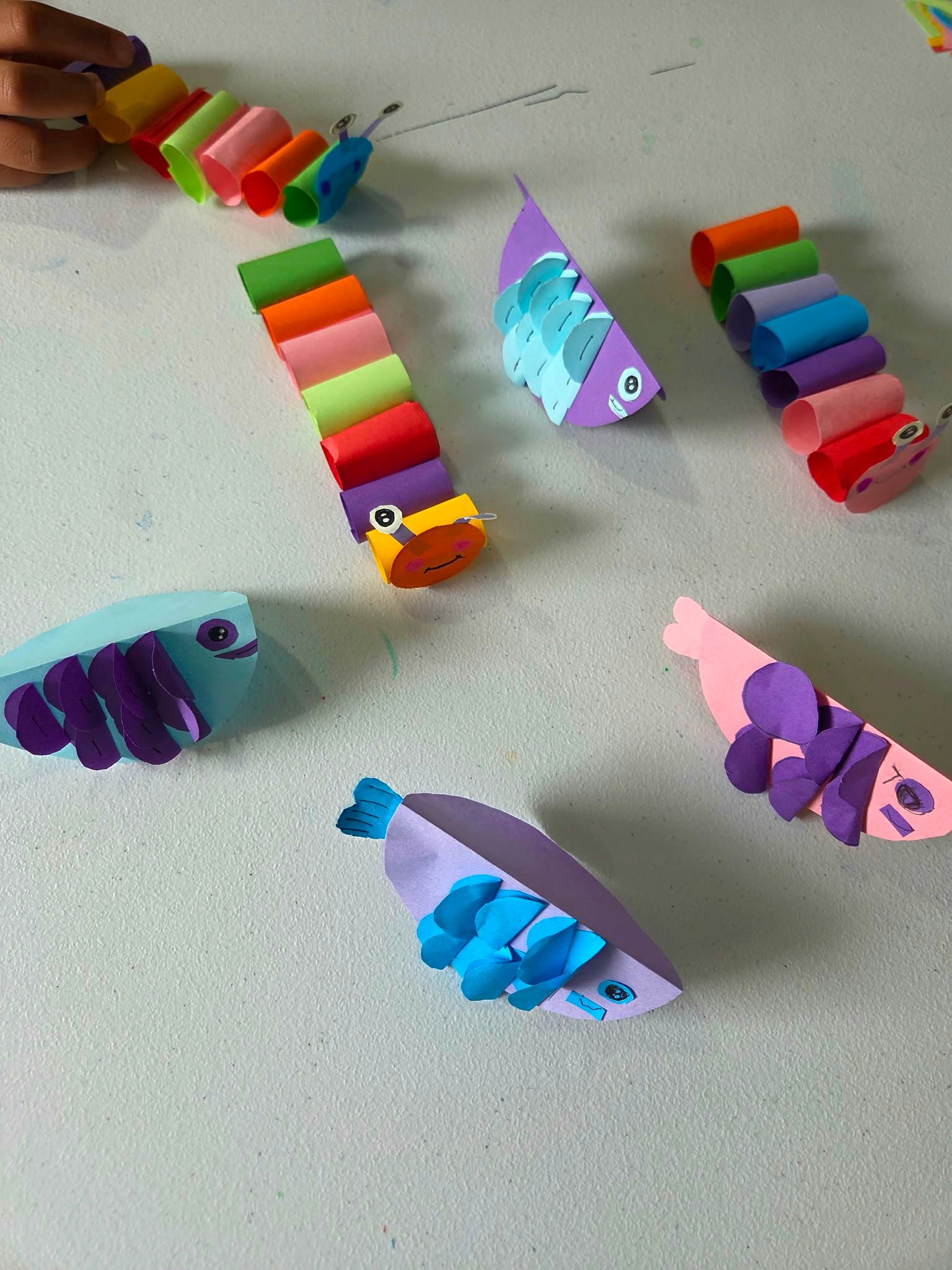 Student Paper Hand Craft — paper fish and caterpillar creations on the craft table