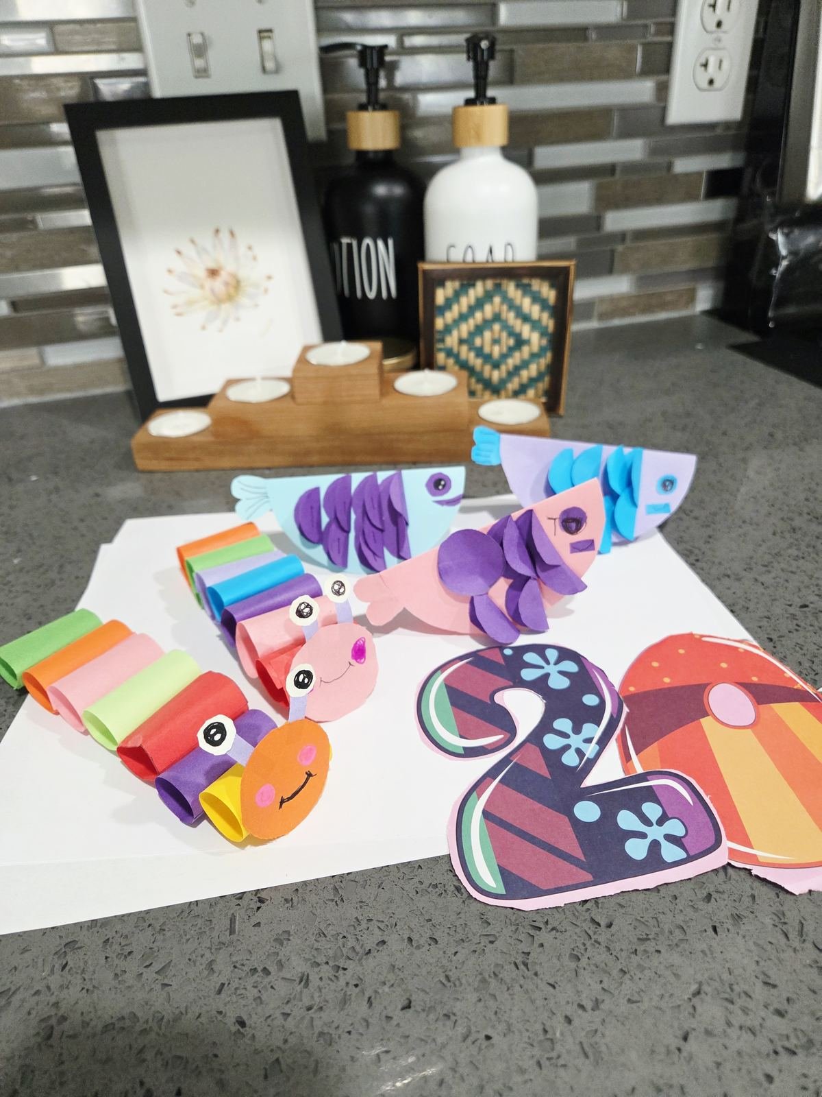 Student Paper Hand Craft — paper fish and caterpillar creations displayed at home